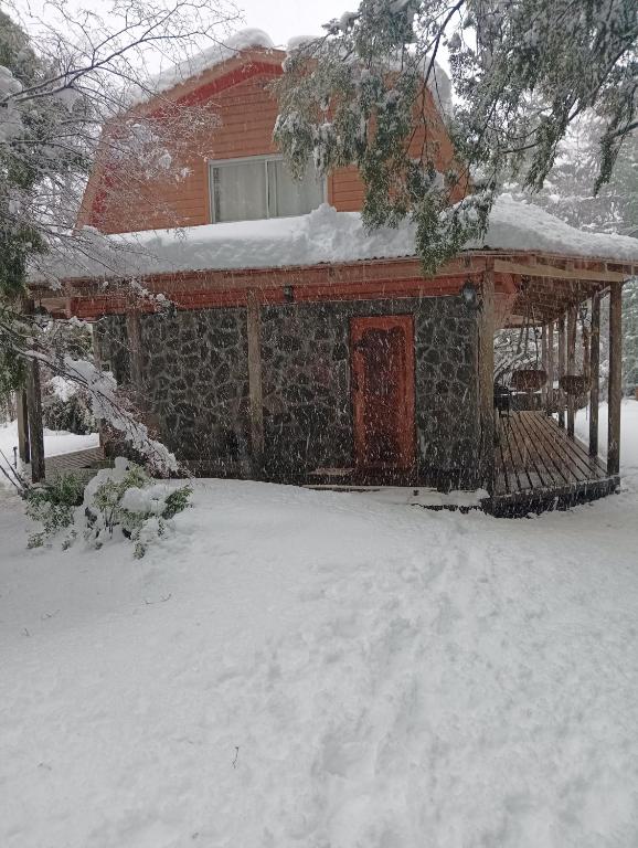 a house with snow on the roof of it at La Cabaña de Piedra in Las Trancas