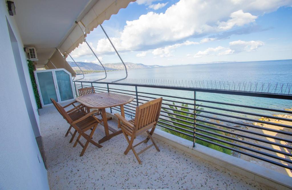 a balcony with a table and chairs and the ocean at Blue Horizon Seafront Apartment in Agioi Theodoroi
