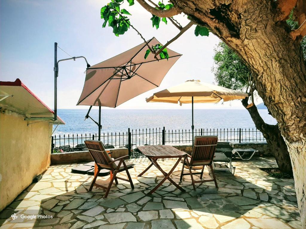 a table and chairs with an umbrella and the ocean at Seafront Villa, Fay in Kardamyli
