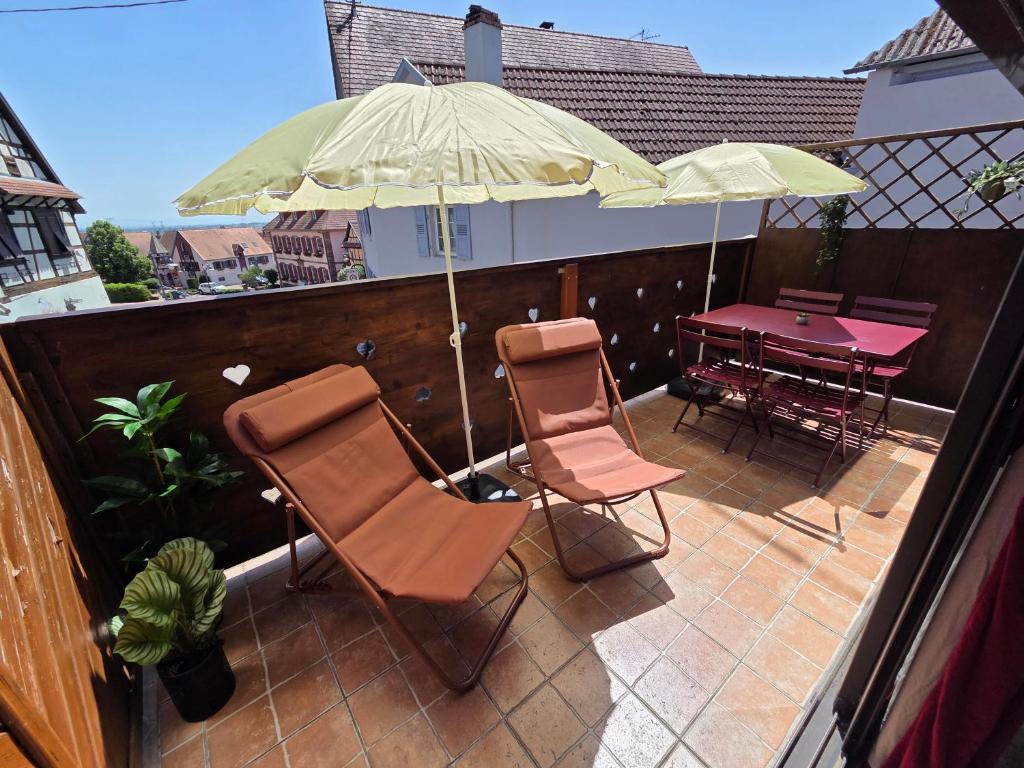 a patio with two chairs and an umbrella and a table at La Maison Kouglof in Nordheim