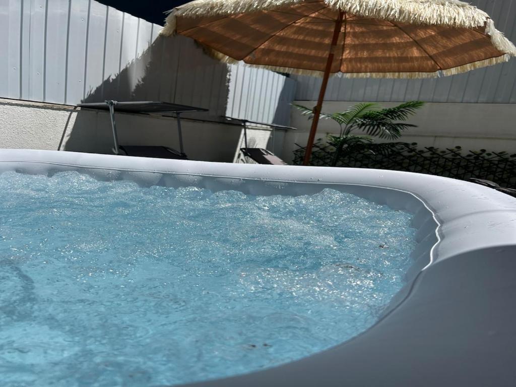 a hot tub with an umbrella next to a table and an umbrella at Aroeira Turquoise Home in Aroeira