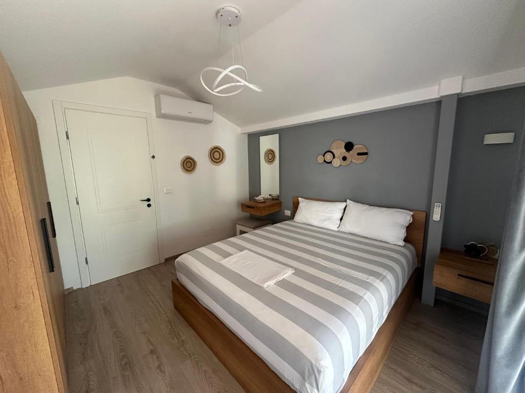 a bedroom with a bed with a white and gray striped bedspread at Garden Beach House in Hamallë