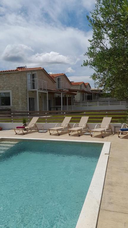 a swimming pool with lounge chairs and a house at Petra Serenity Villas in Afitos