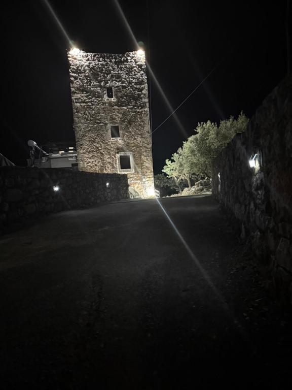 a stone tower with lights on it at night at Nigos in Okhiá