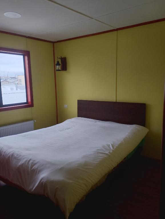 a bedroom with a large white bed with a window at Casa rayen in Puerto Natales