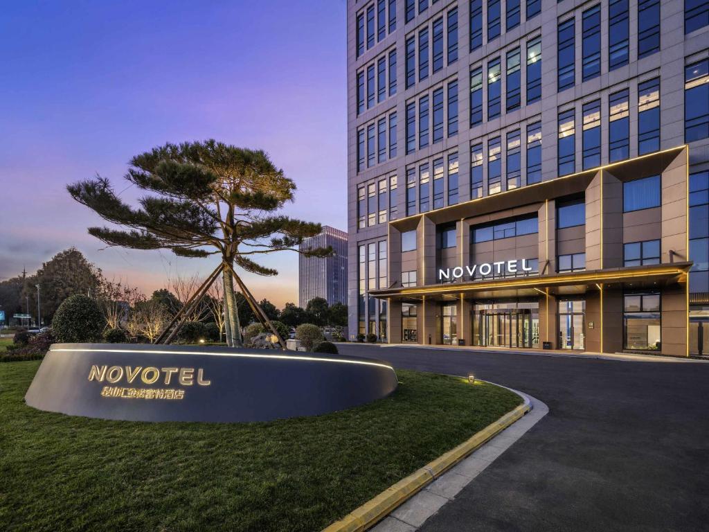 a large building with a tree in front of it at Novotel Kunshan Yangcheng Lake in Kunshan