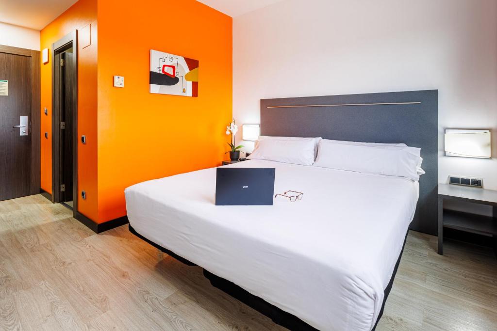 a bedroom with a bed with a laptop on it at H2 Fuenlabrada in Fuenlabrada