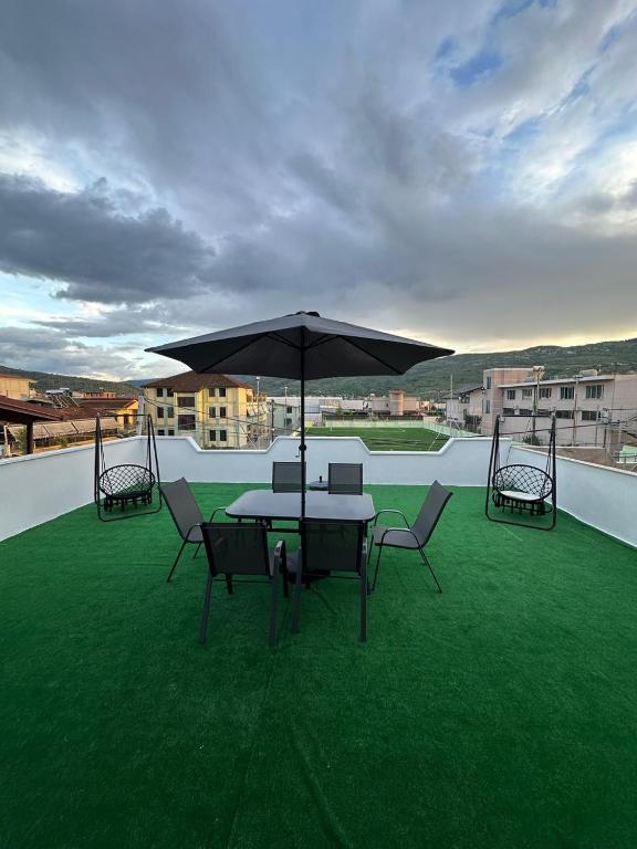 a patio with a table and chairs and an umbrella at Green Berat Villa in Uznovë