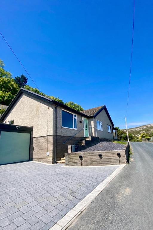 a house with a garage on the side of a street at Amarons Nest - Cosy little house on Great Orme in Llandudno