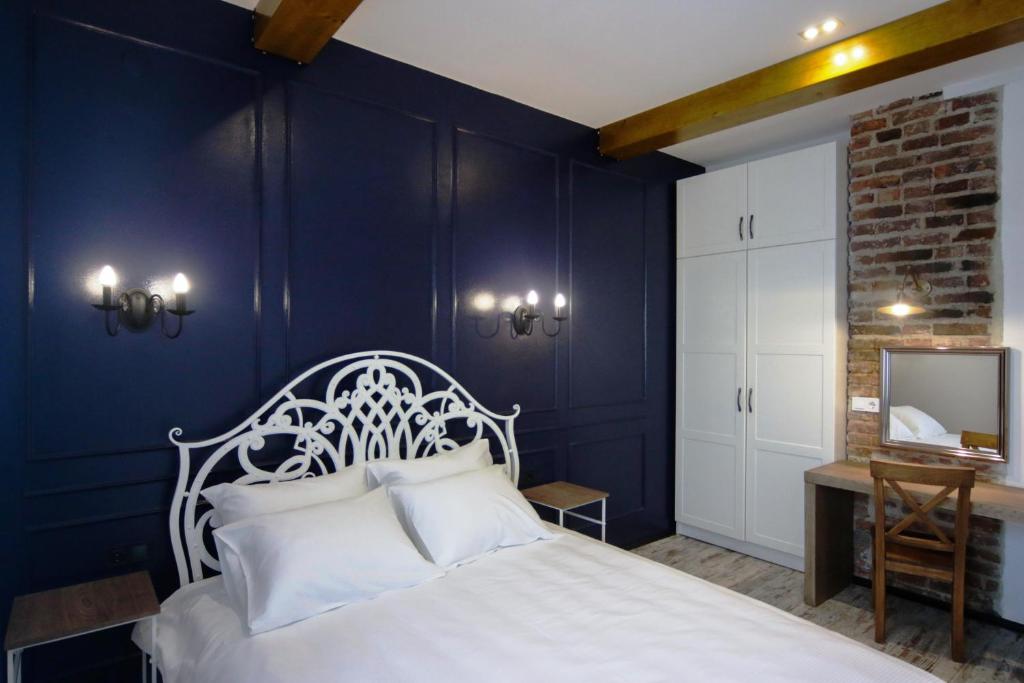 a bedroom with a white bed and a blue wall at Potocki Apartments in Lviv