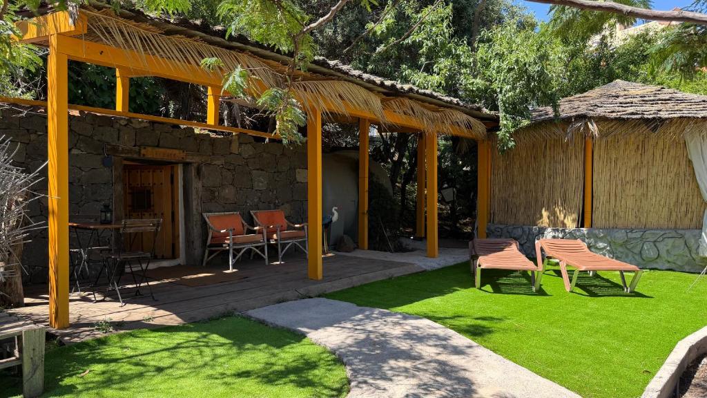 a house with a patio with chairs and grass at El Refugio de Las Vegas in Valsequillo