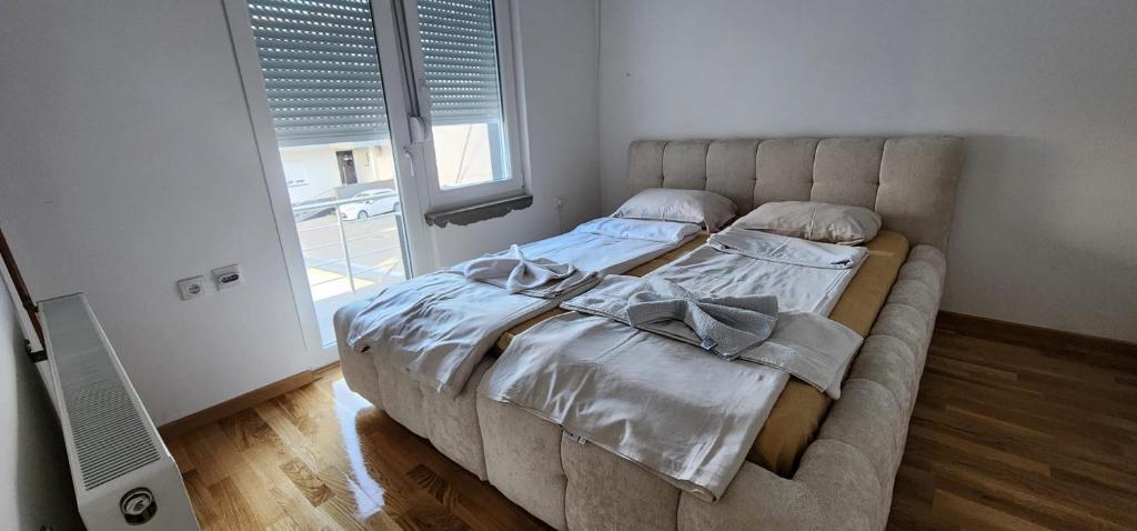 a bed in a bedroom with a large window at mala Atina in Petrovaradin
