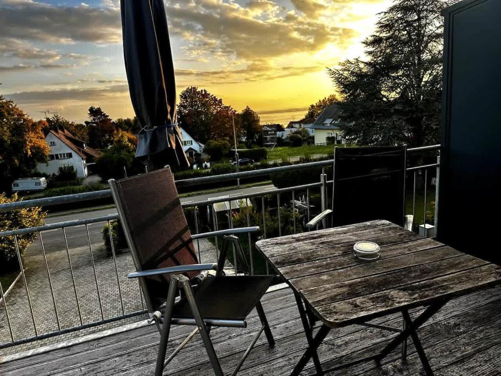 a wooden table and chair on a deck with an umbrella at STAY - Seeblick Apartment in Friedrichshafen