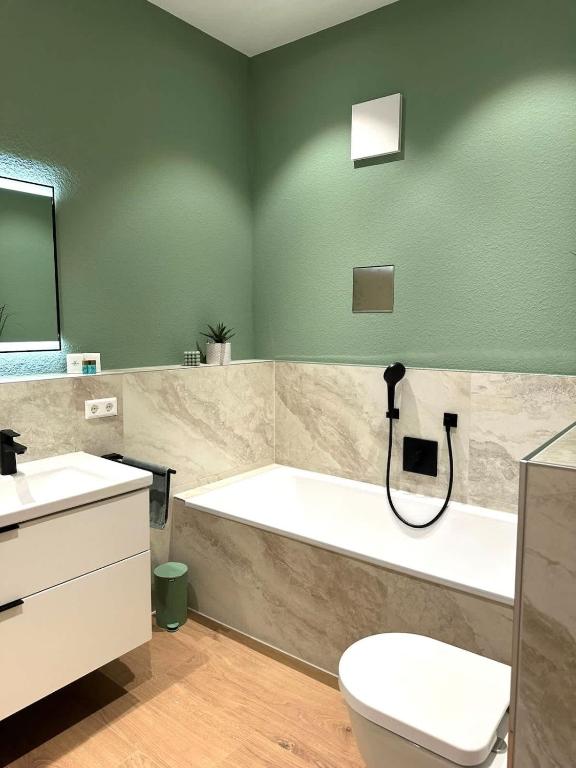 a bathroom with a tub and a toilet and a sink at STAY - City M17 in Tettnang