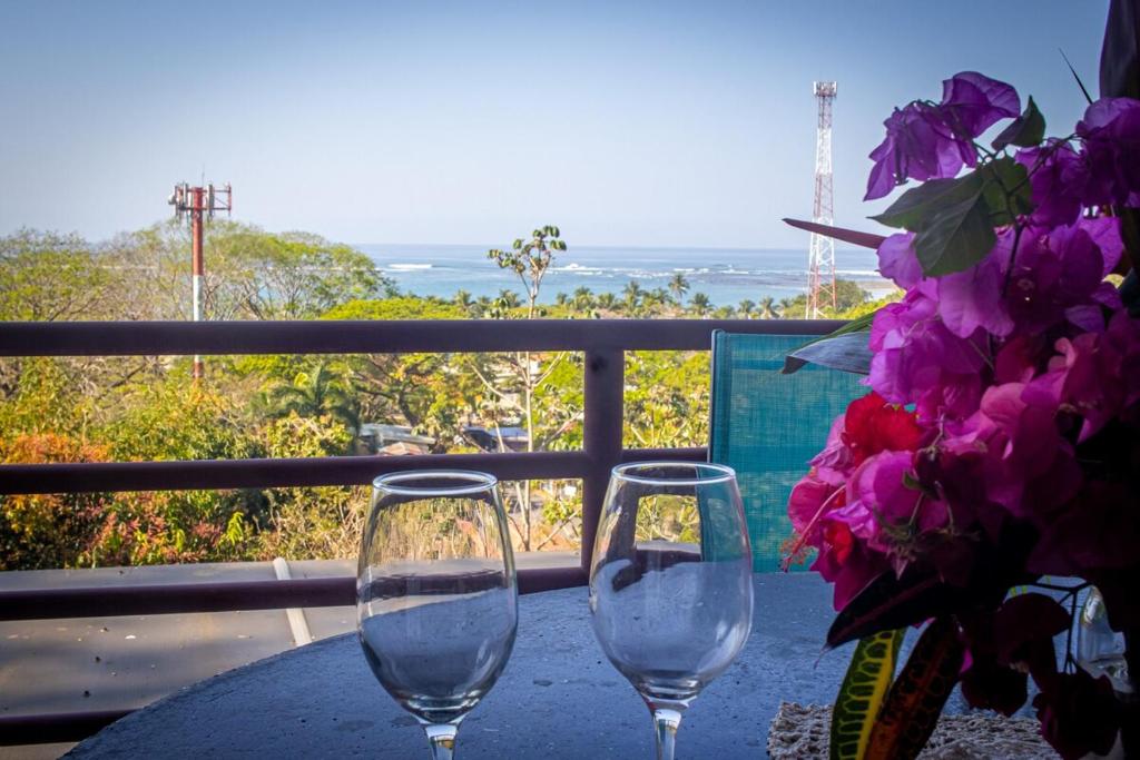 two wine glasses sitting on a table on a balcony at Samara Ocean View in Sámara