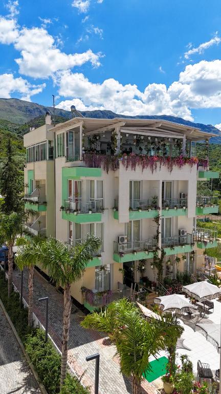 a large building with palm trees in front of it at Hotel Garden in Vlorë