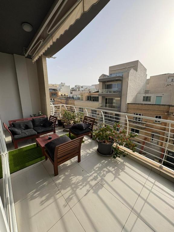 a balcony with chairs and tables on a building at Grand Residence 3-Bedroom Spacious Premium Central Apartment in Is-Swieqi