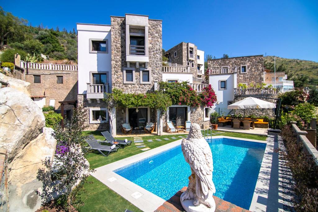 a villa with a bird statue in front of a swimming pool at Villa Stone Bodrum - Private Pool & Garden in Bodrum City