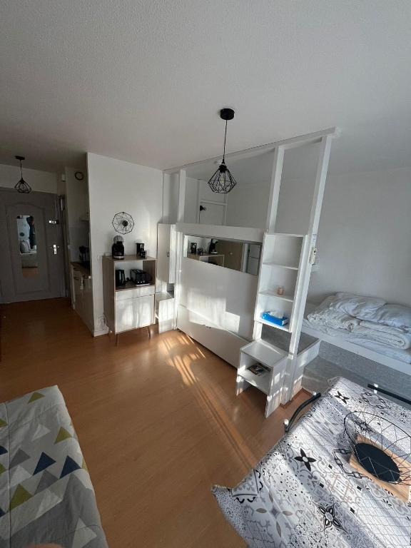 a bedroom with white walls and a bed and a wooden floor at Studio cabine Canet Plage Parking in Canet-en-Roussillon