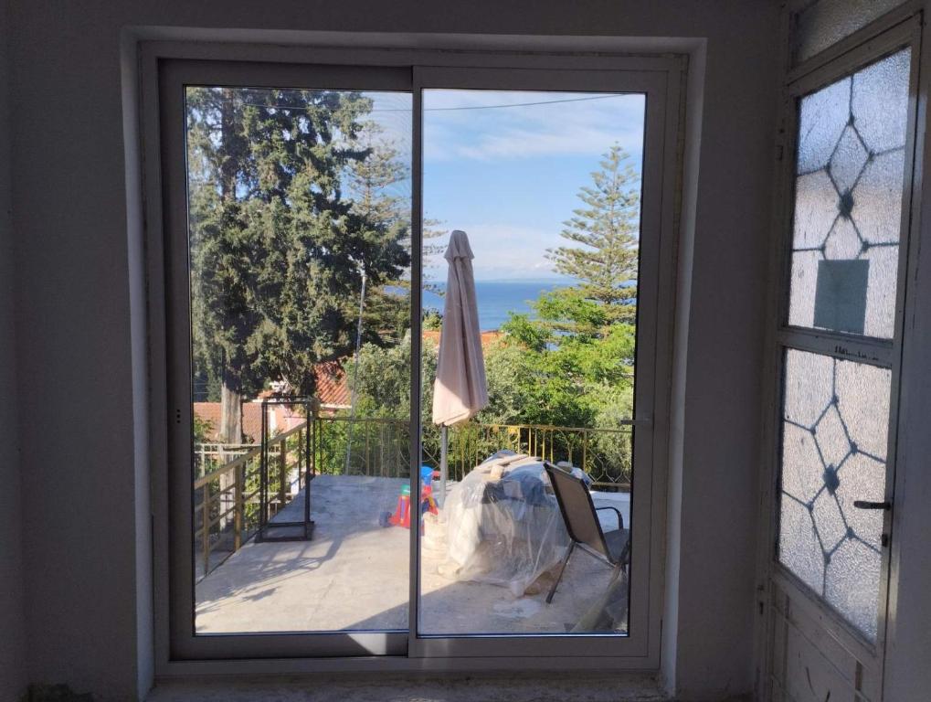 a window with a view of a patio with an umbrella at REPANTALIA Apartment in Zakynthos
