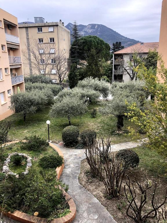 a garden with trees and bushes in a city at Appartement moderne climatisé in Nyons
