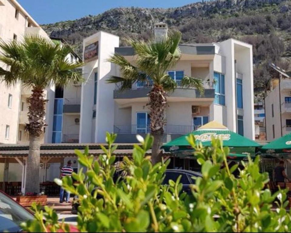 two palm trees and umbrellas in front of a building at Vila Era in Shëngjin