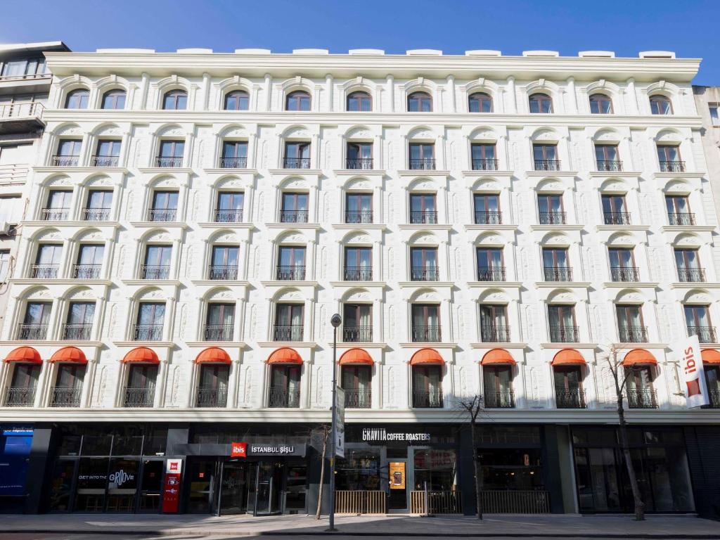 a large white building with orange awnings on it at ibis Istanbul Sisli in Istanbul