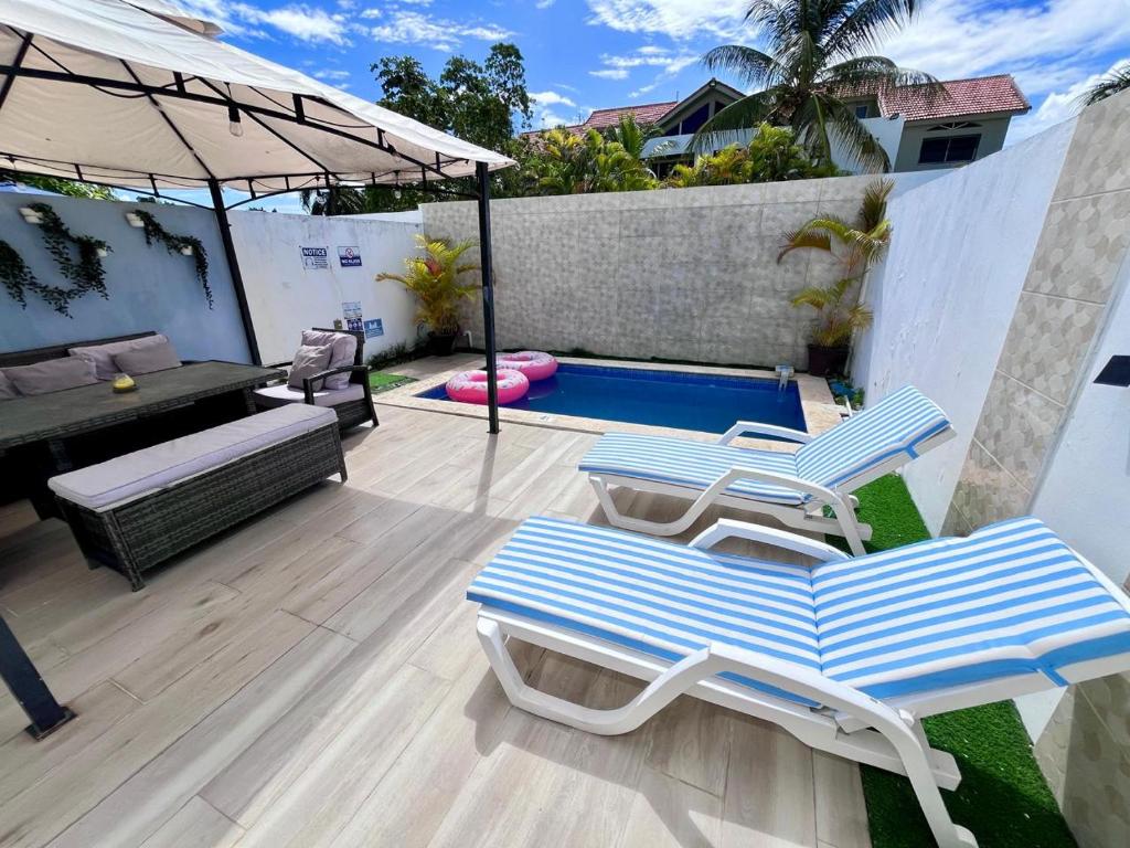 a patio with two lounge chairs and an umbrella at Private pool villa with jacuzzi, near beaches in Punta Cana