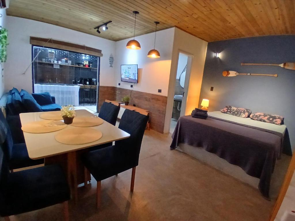 a dining room with a table and a bed in a room at Apartamento em juquehy in São Sebastião