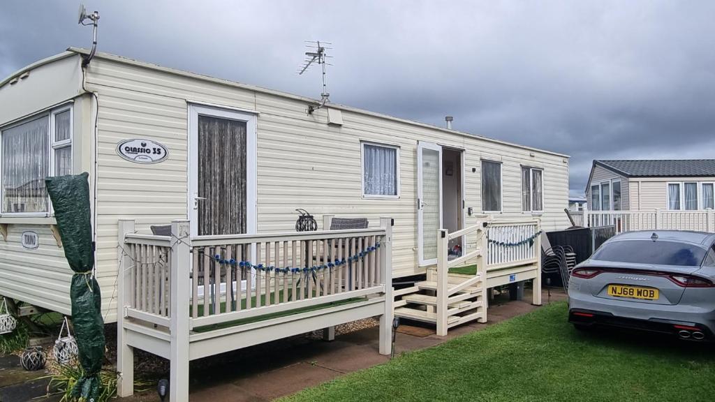 a white caravan with a car parked in front of it at Golden sands 326 3 bedroomed caravan in Ingoldmells