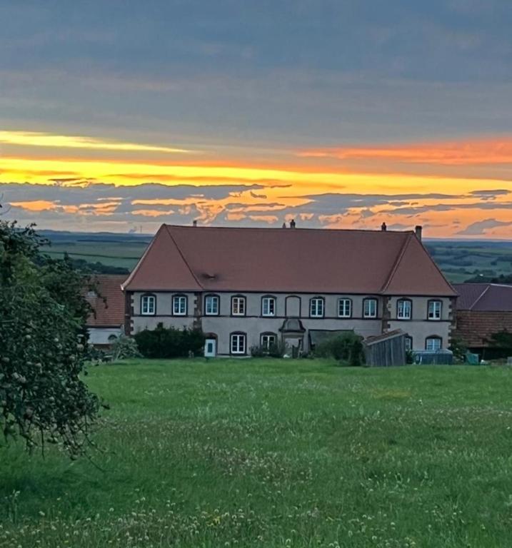 a house on a field with a sunset in the background at Chateau de Gendersberg in Hanviller
