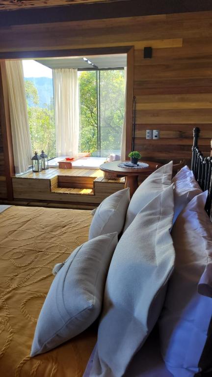 a bed with white pillows in a room with a large window at Cabana Zermatt in Timbe do Sul
