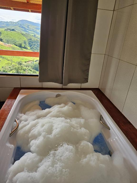 a bath tub filled with clouds in front of a window at Oasis na montanha in Bueno Brandão