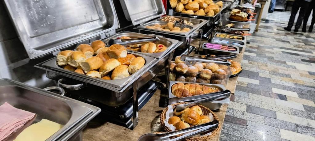 a buffet line with trays of bread and pastries at Hotel Benfica in Aparecida