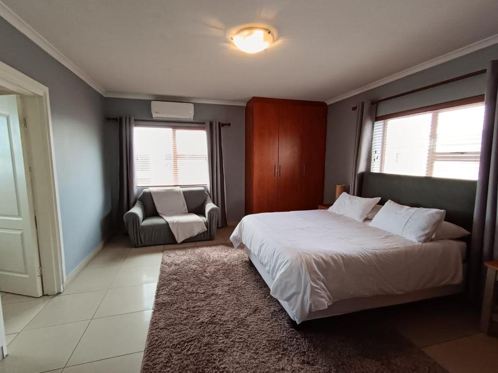 a bedroom with a bed and a chair and windows at Toekies and Abel in Cape Town