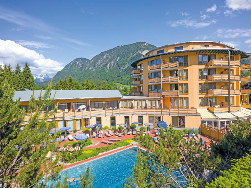 a hotel with a pool and mountains in the background at Vivea Gesundheitshotel Bad Häring in Bad Häring