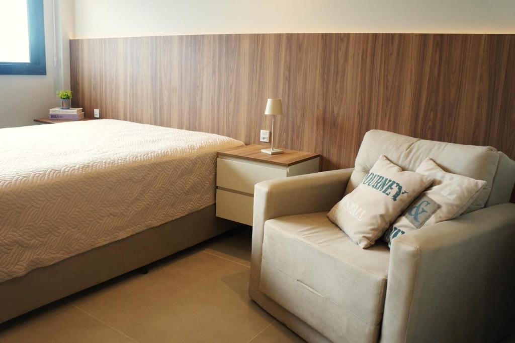 a bedroom with a bed and a chair and a bed petertodd at Studio moderno no coração da Cidade Baixa in Porto Alegre