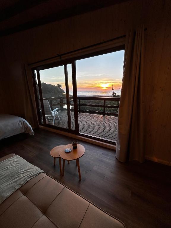 a room with a bed and a table in front of a window at Piedra Amarilla Tiny House in Curanipe