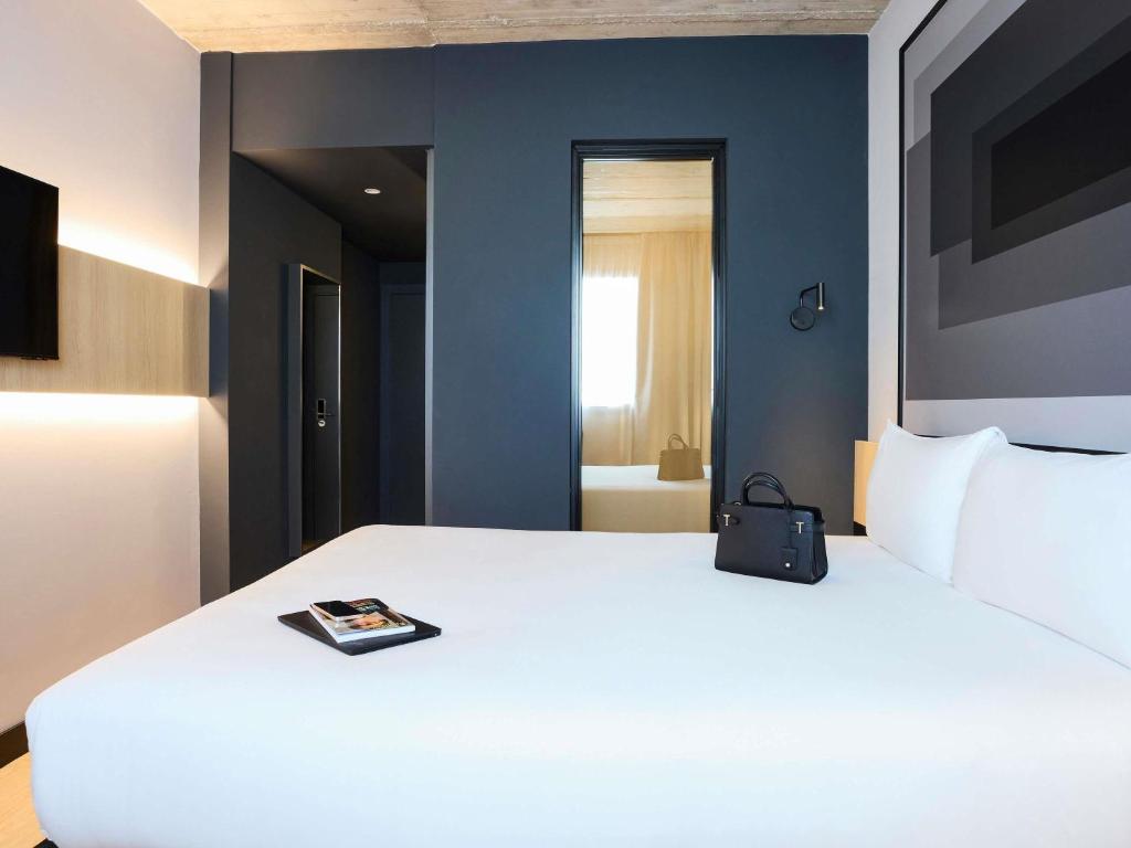 a bedroom with a white bed with a book on it at ibis Madrid Norte Las Tablas in Madrid
