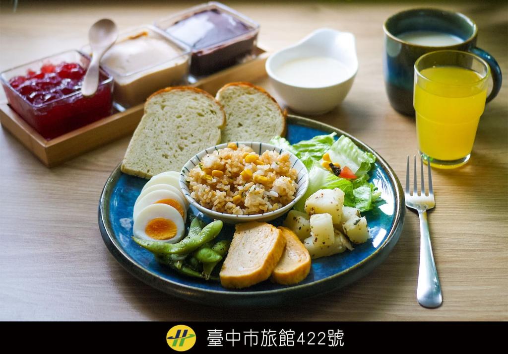 a plate of food with bread and vegetables and a glass of orange juice at Loosha Hostel in Taichung