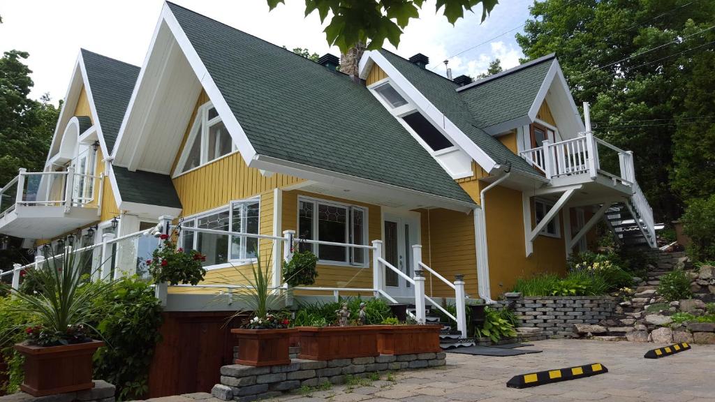 una casa amarilla con techo verde en Gîte Au Perchoir en Baie-Saint-Paul