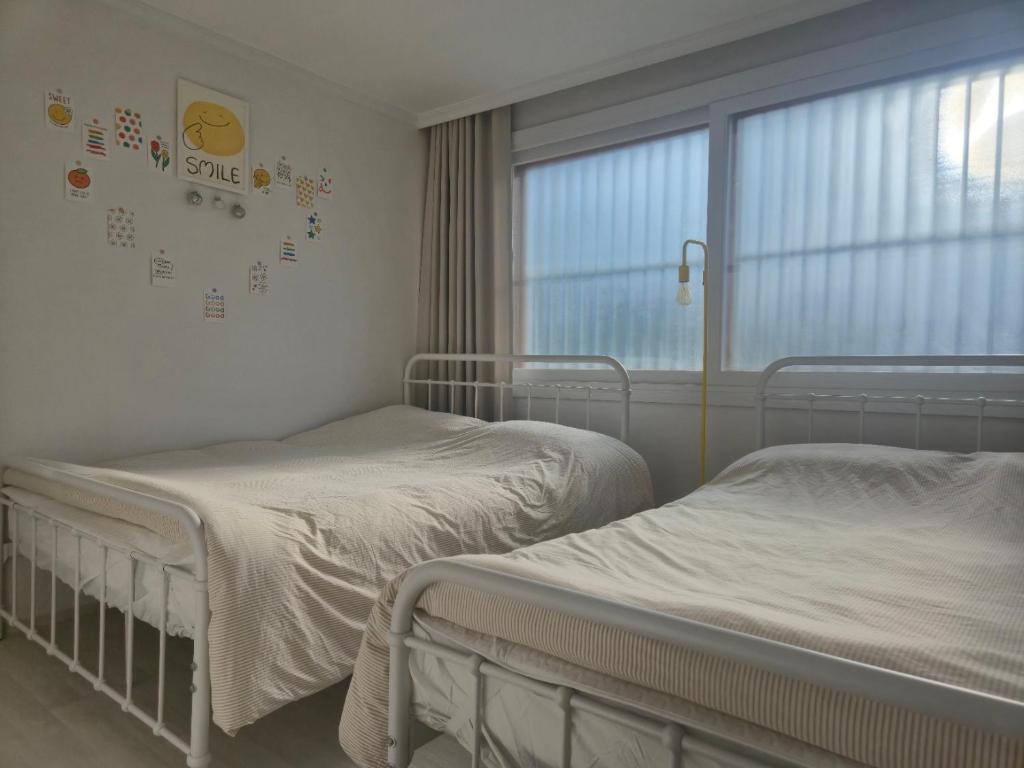 two beds in a hospital room with a window at Suwon Cozy Stay in Suwŏn-yŏk