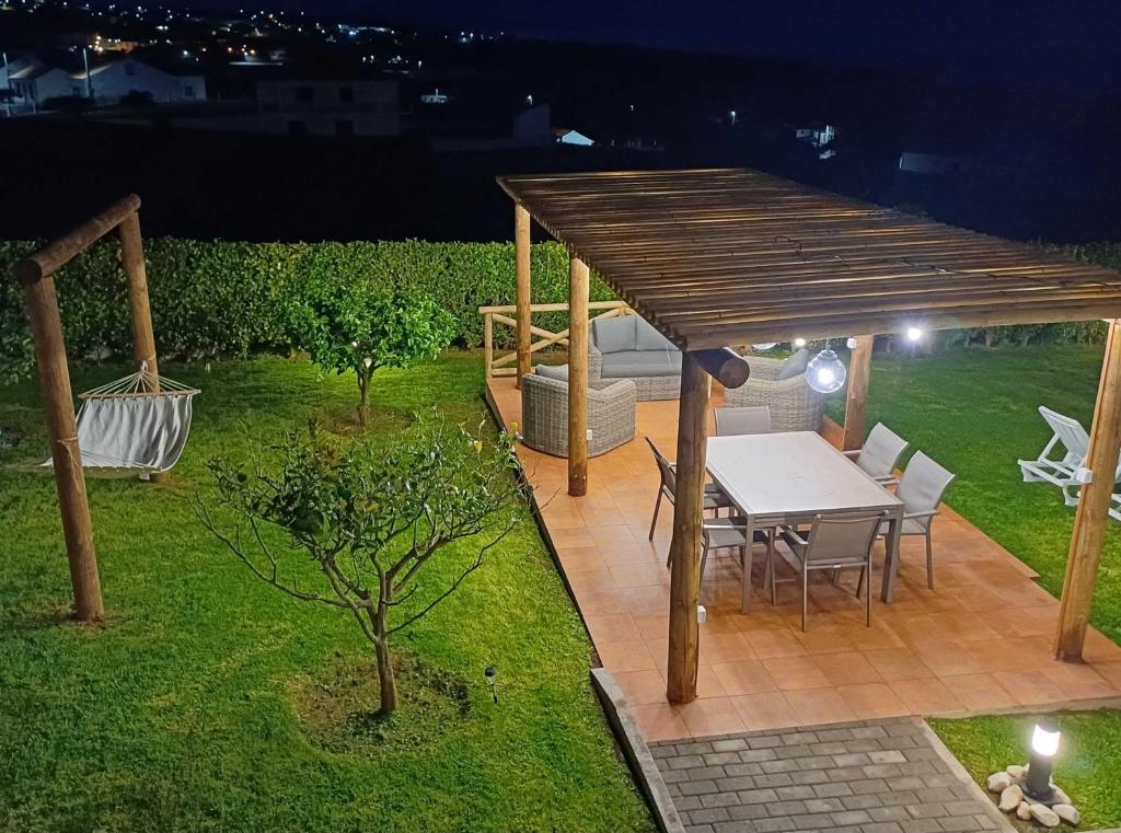 a wooden pergola with a table in a garden at night at Casa do Galante in Nordeste