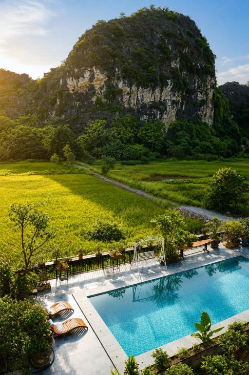 a pool with chairs and a mountain in the background at Tam Cốc AppA House in Ninh Binh