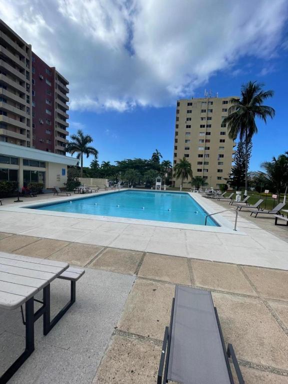 a swimming pool with two benches and two buildings at Towers by the Beach in Ocho Rios