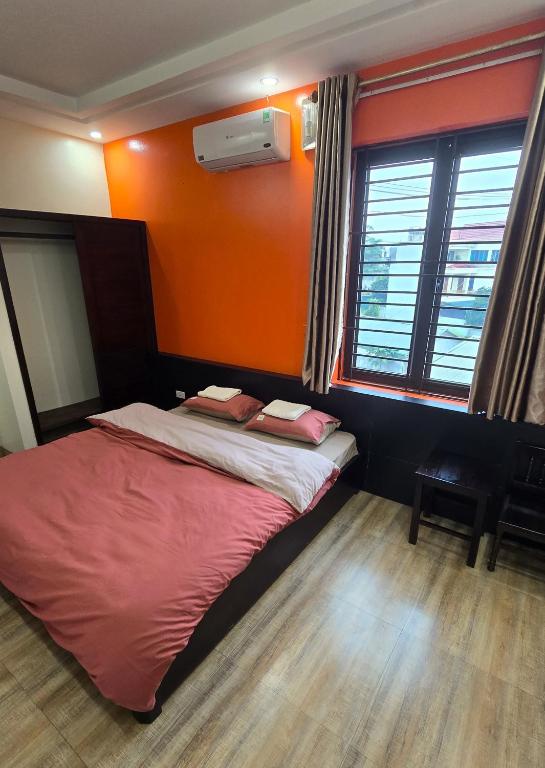 a bed in a room with an orange wall at Ha Giang SkyPath Hostel & Tours in Làng Lap