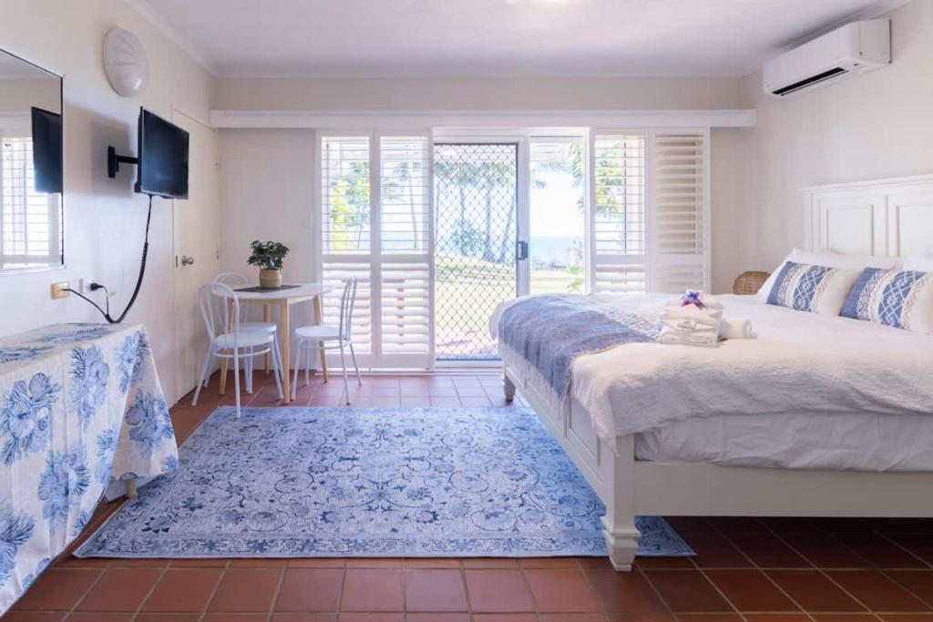 a bedroom with a bed and a table and a balcony at The Sunset Sea in Eimeo