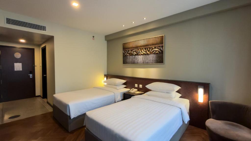 ein Hotelzimmer mit zwei Betten und einem Stuhl in der Unterkunft Hotel Royal Singapore in Singapur