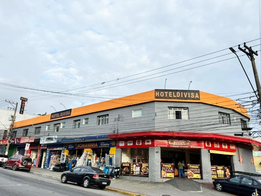 a building on a street with cars parked in front of it at Hotel Divisa poá in Poá
