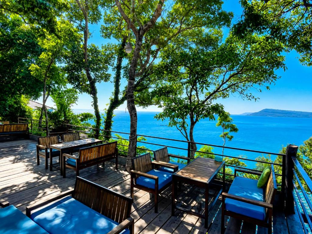 a deck with tables and chairs overlooking the water at The Cliff Bungalow in Koh Rong Sanloem